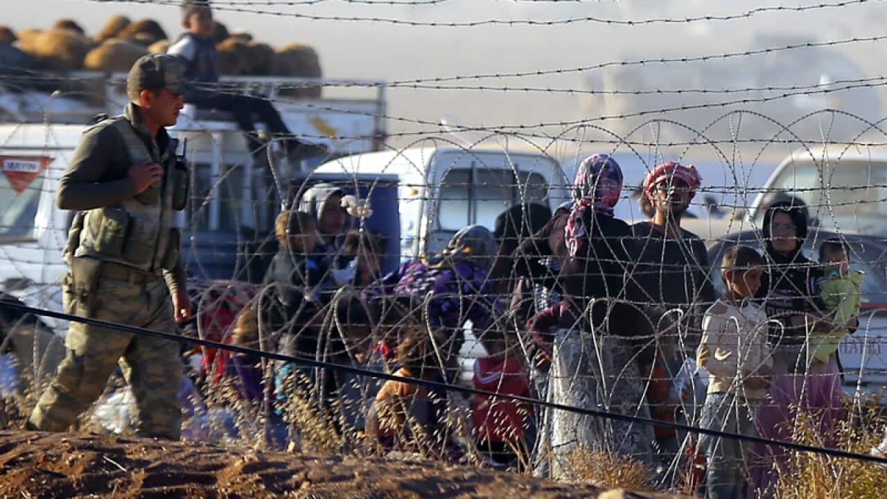 Syrian refugees wait near the Turkish-Syrian border