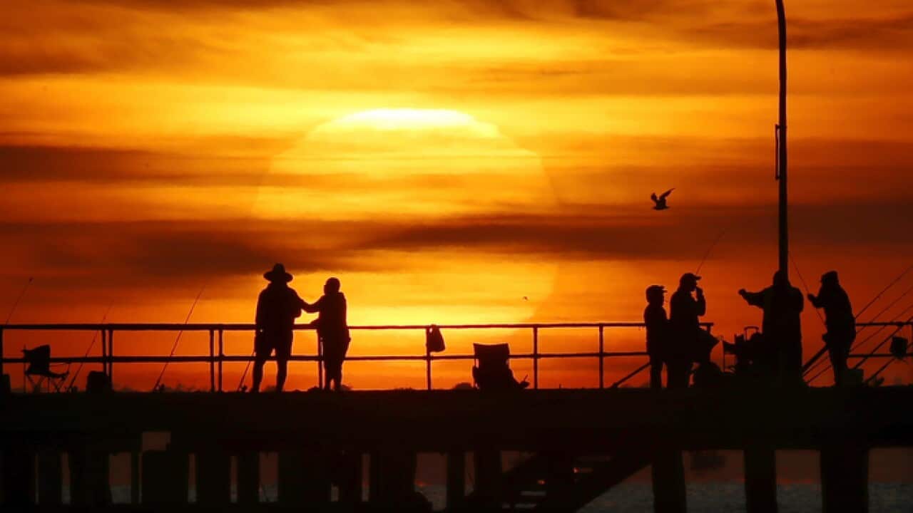 People are watching the sunrise over Altona Pier in Melbourne.