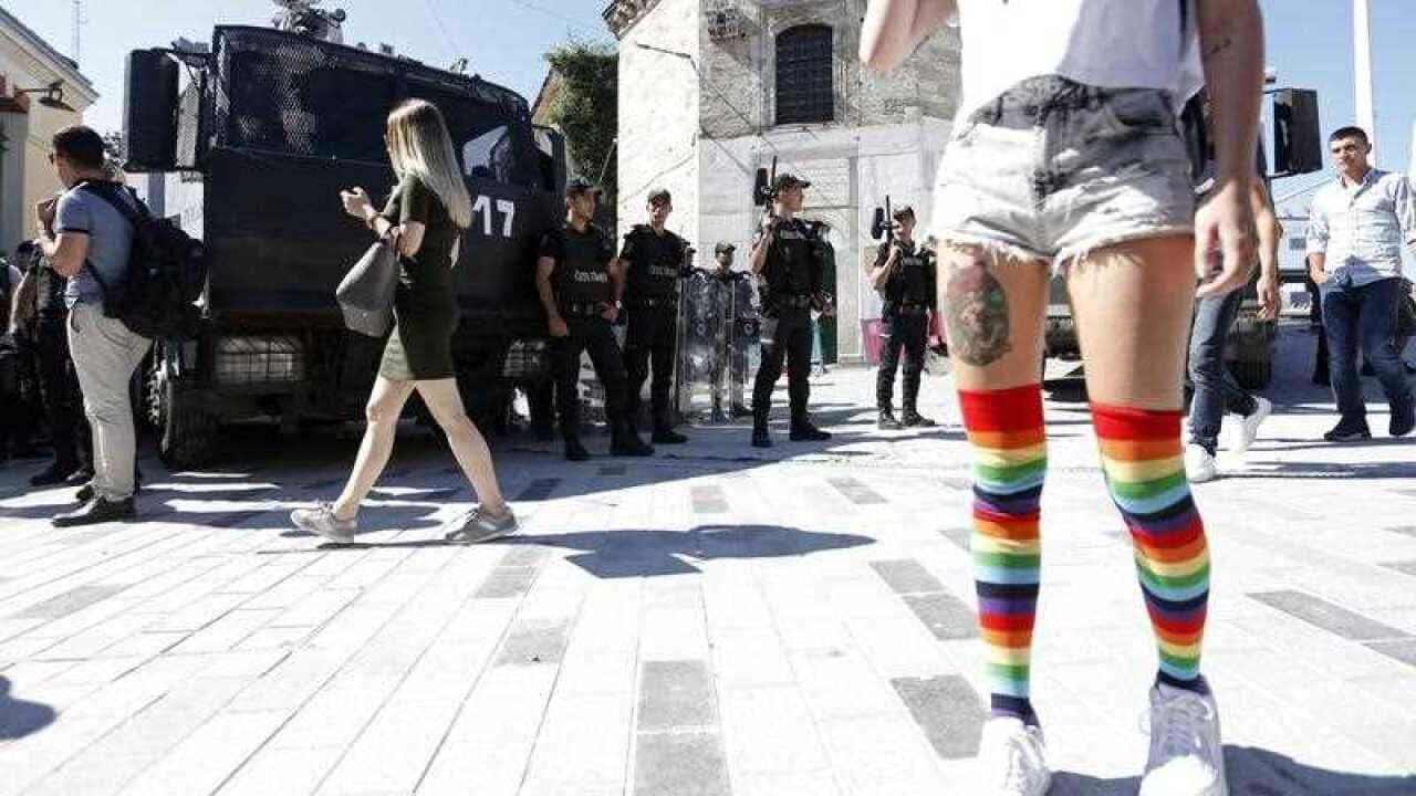 A participant waits in front of Turkish police during the Istanbul Pride Parade