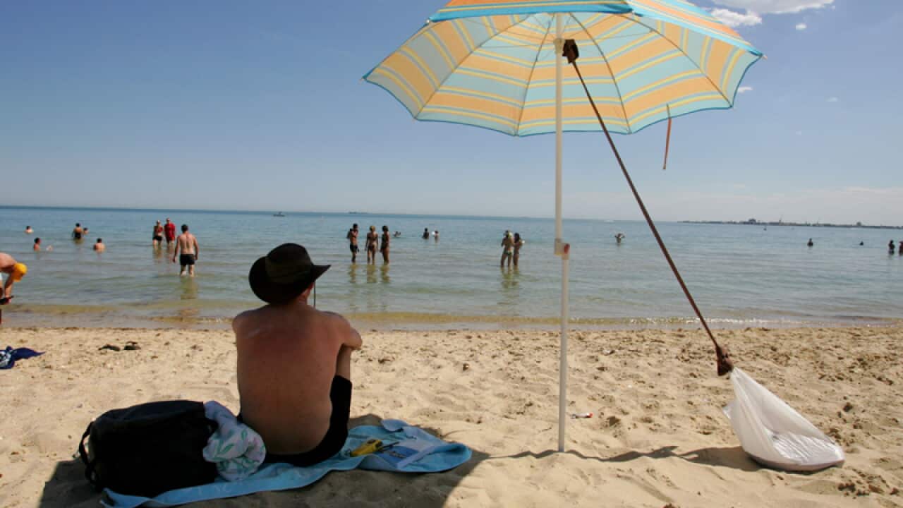 A man seeks shelter under an umbrella