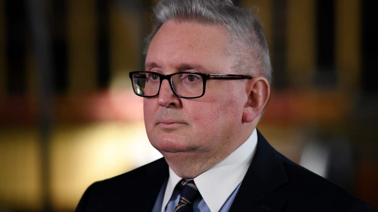 Don Harwin wearing glasses and wearing a suit. A blurry background is behind him.