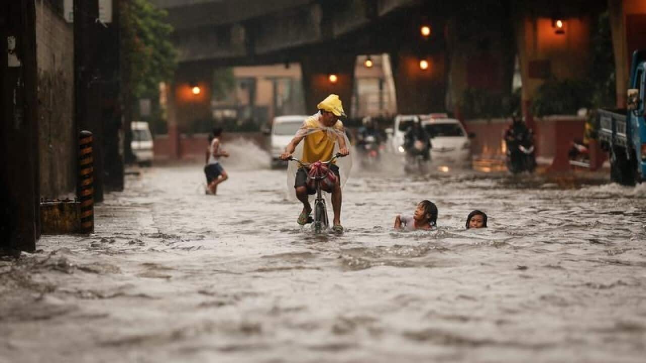 A Filipino on a bike passes in a flooded street in Manila, Philippines