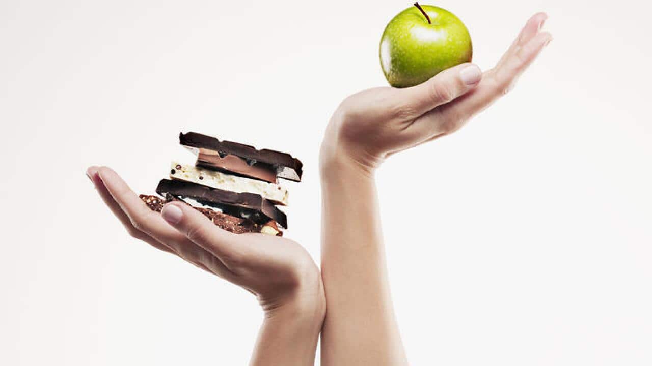 Woman cupping green apple above chocolate bars