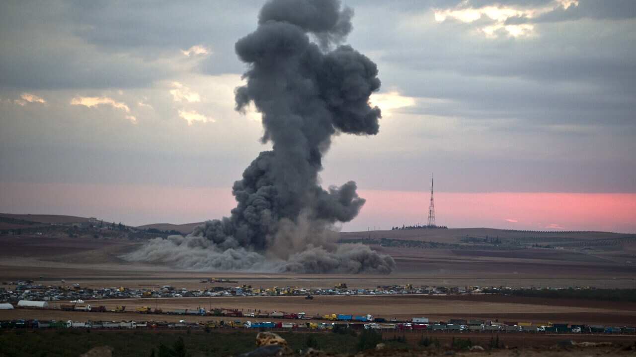 Smoke from an airstrike by the US-led coalition rises outside Kobani, Syria, as seen from a hilltop on the outskirts of Suruc, at the Turkey-Syria border (AAP)