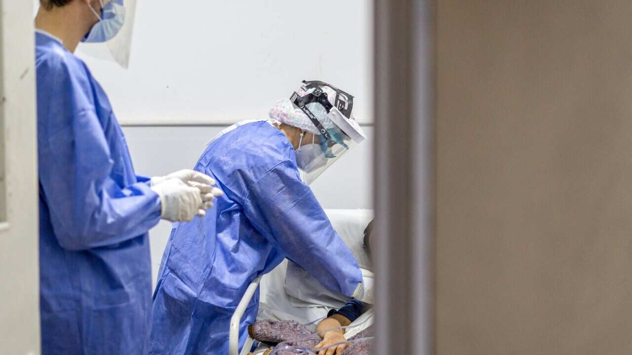 A nurse checks on a coronavirus patient.