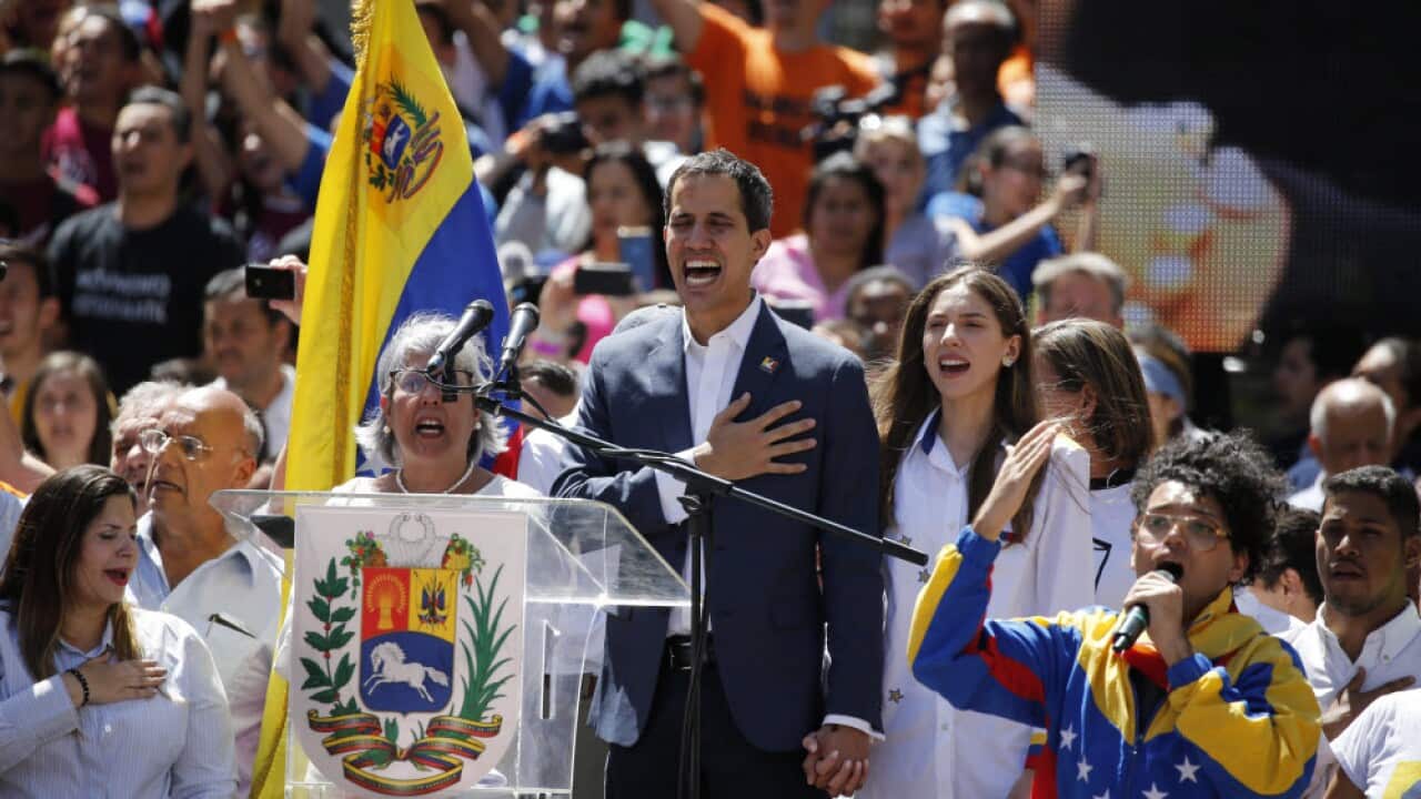 Venezuela' self-proclaimed interim president Juan Guaido sings the national anthem as thousands march against President Nicolas Maduro.