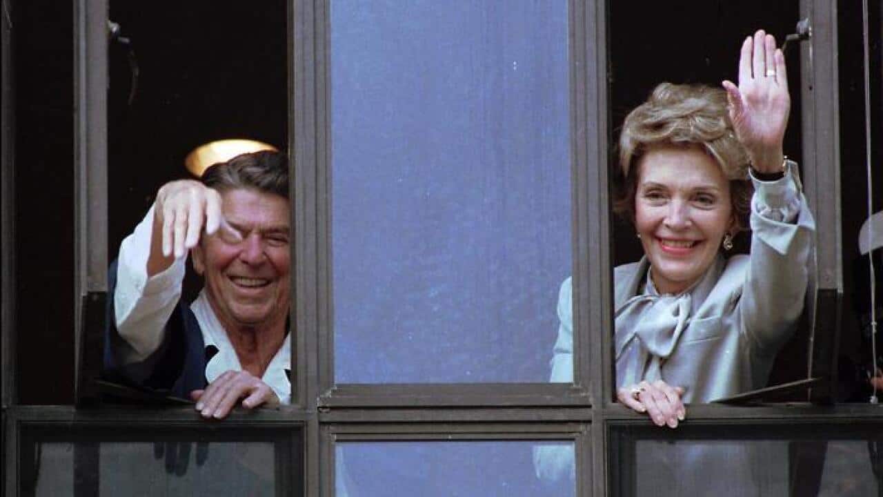 File photo: President Ronald Reagan and his wife, Nancy, wave from windows of his hospital room at the Navy Medical Center in Bethesda, Md. (AAP)