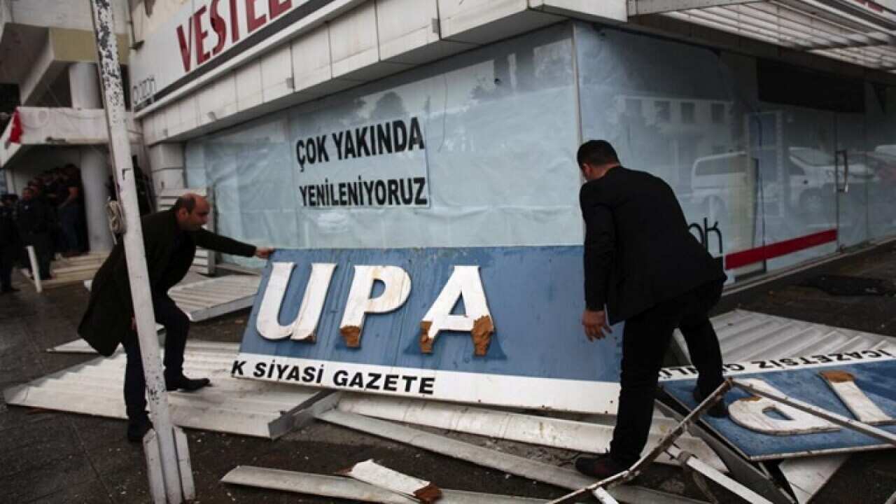 Men hold up the sign of Turkish Cypriot newspaper Afrika, which was attacked by supporters of Turkish President Tayyip Erdogan.