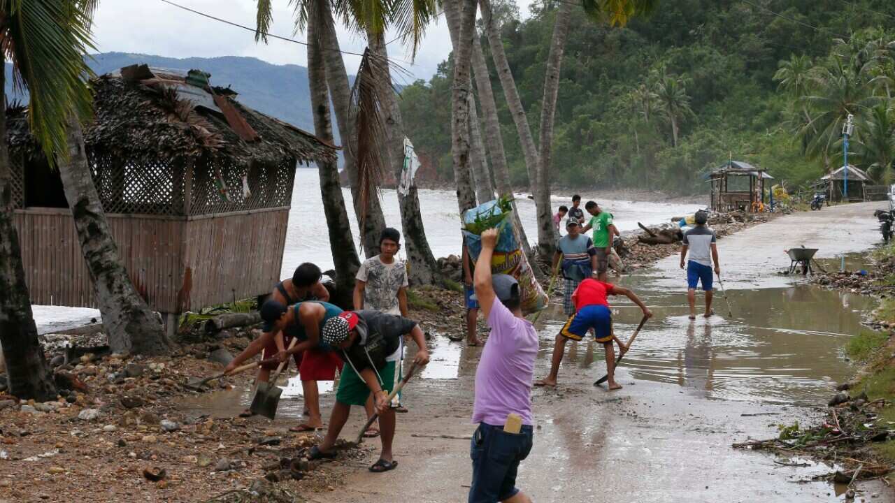 Residents clean the road a day after typhoon Nock-Ten hit Mabini township, Batangas province south of Manila, Philippines on Monday, Dec. 26, 2016.