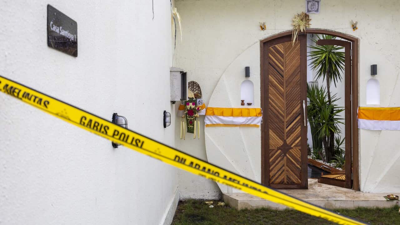 A white Balinese villa has the door open and yellow police in front closing it off