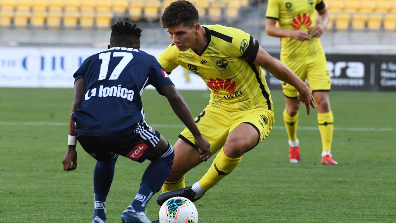 Liberto Cacace of the Phoenix (R) is challenged by Elvis Kamsoba of the Melbourne Victory during their Round 23 A-League match in Wellington.