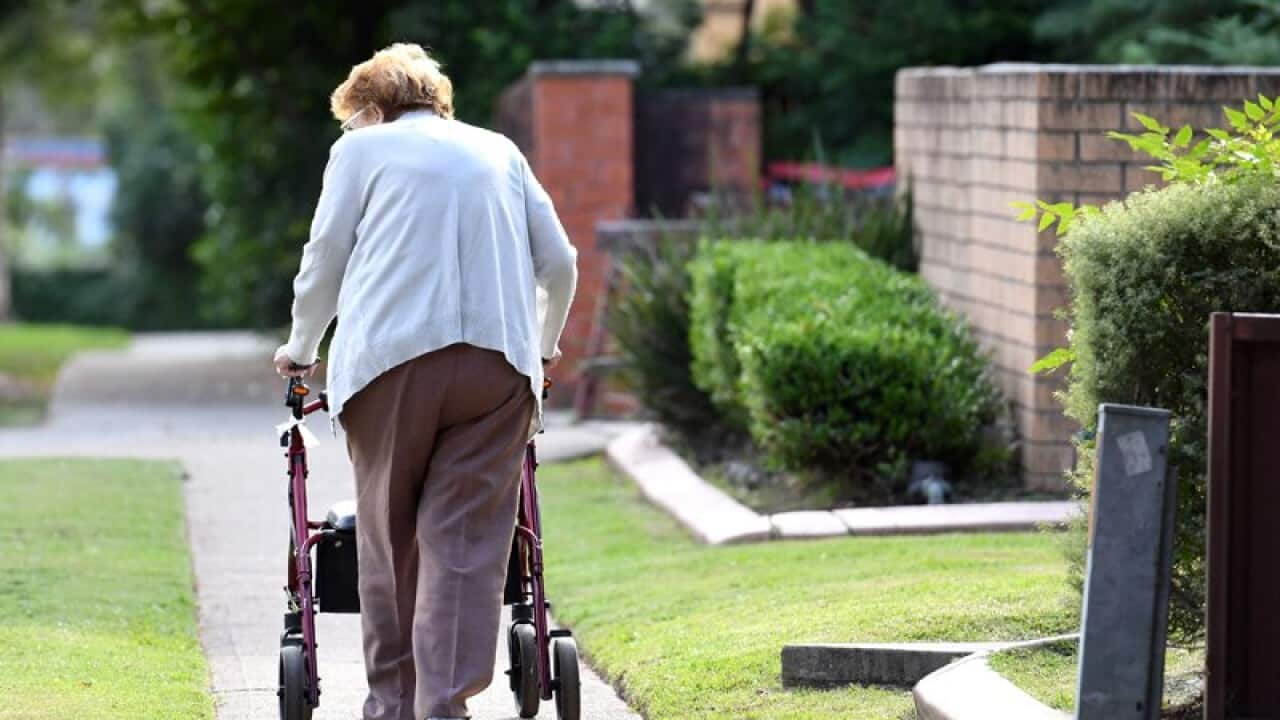 An elderly woman uses a mobility walker