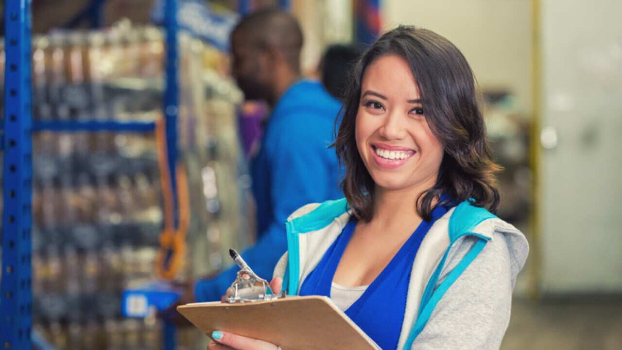 Happy woman volunteering in charity food bank warehouse, taking inventory