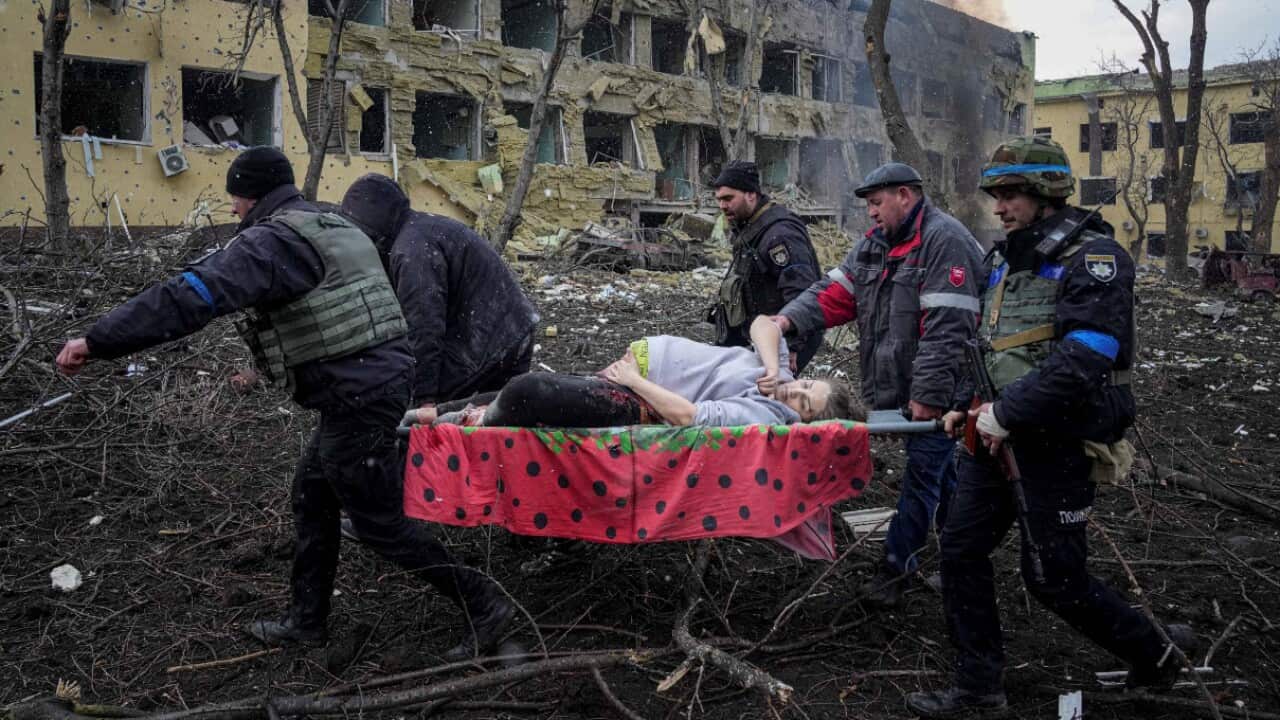 Una barella trasporta il corpo senza vita di una giovane madre uccisa nel bombardamento di Mariupol