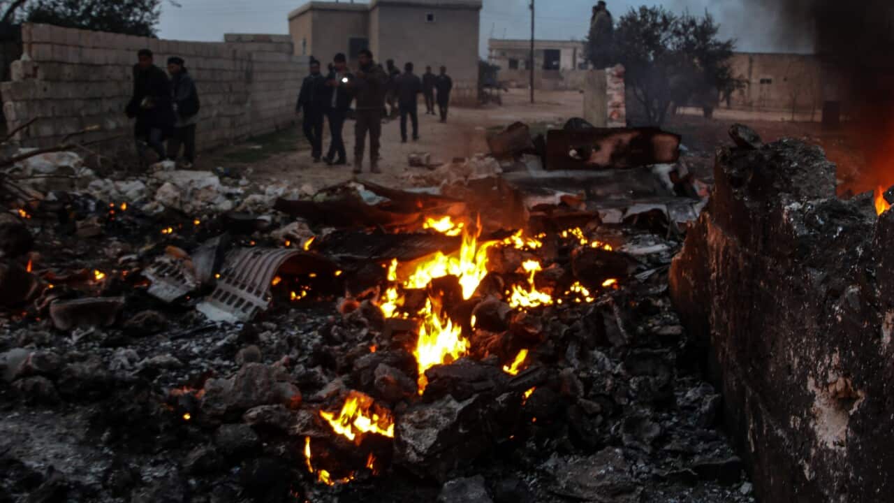 People walk amidst the rubble of the Russian Sukhoi Su-25 fighter jet scattered on the ground.