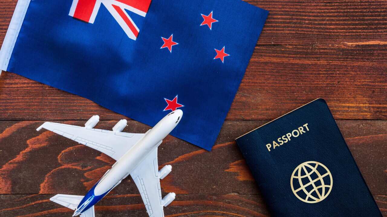Flag of New Zealand with passport and toy airplane on wooden background