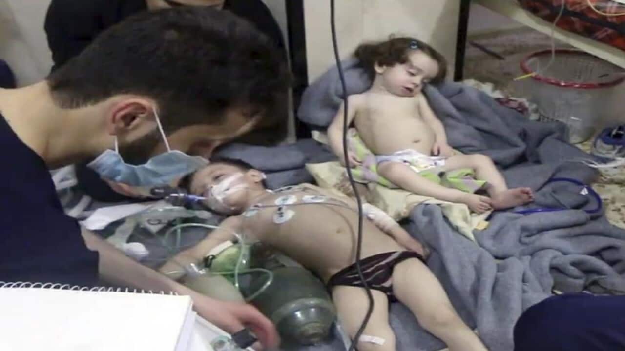 A medical worker treats toddlers after an alleged poison gas attack