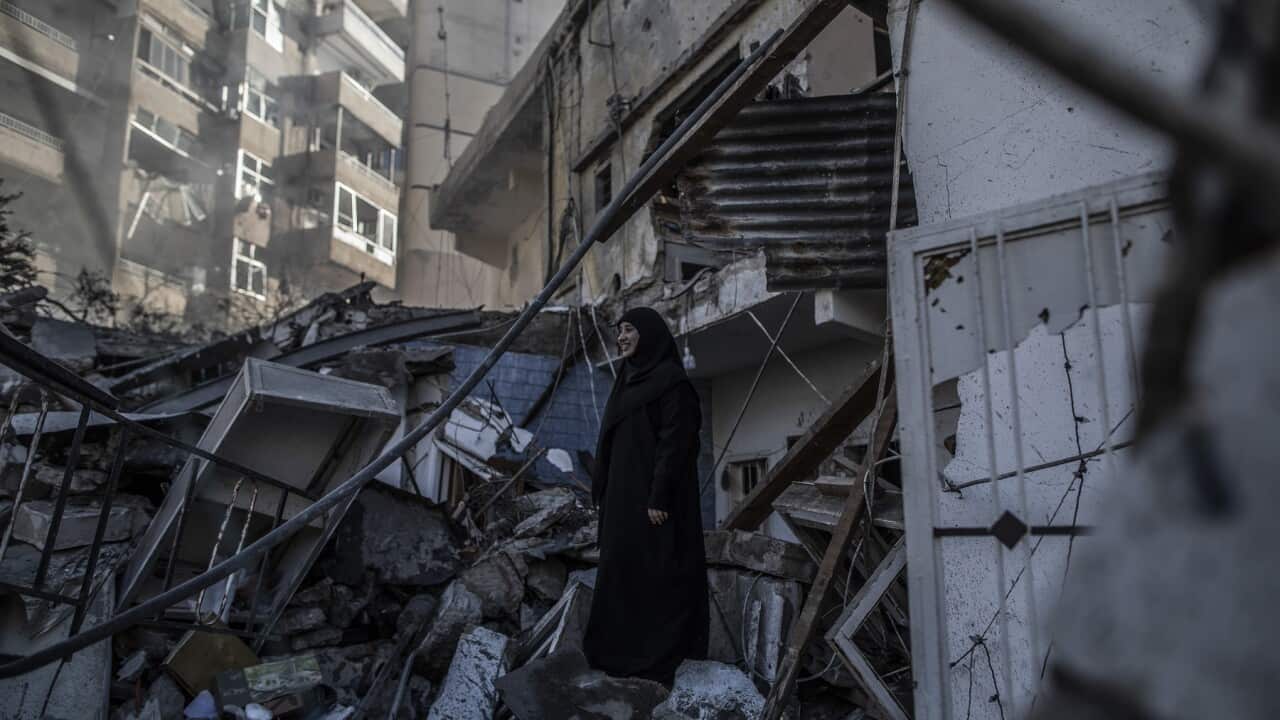 A woman stands amid damage from a destroyed building