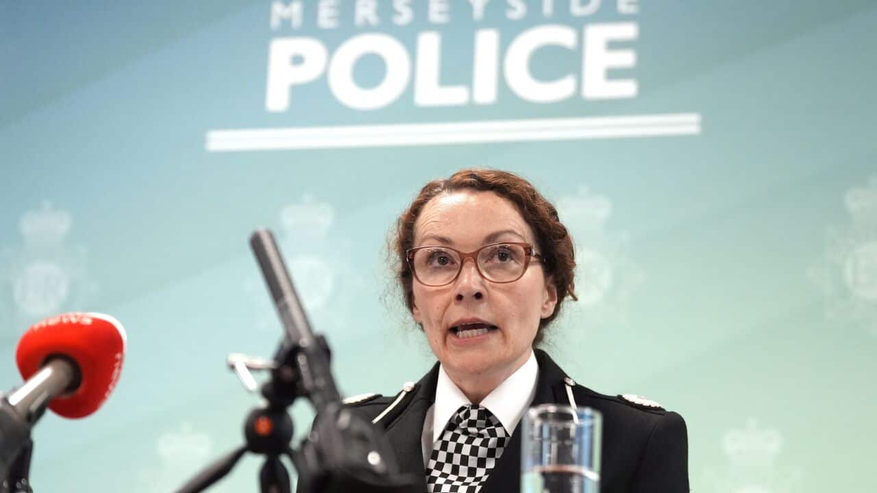 A woman in a police uniform is speaking into a microphone.