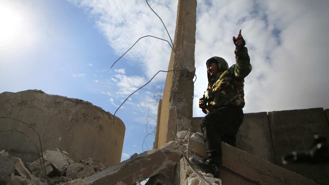 A Kurdish-led Syrian Democratic Forces fighter, stands at a damgaed part of the defense wall of Gweiran Prison, in Hassakeh, northeast Syria.