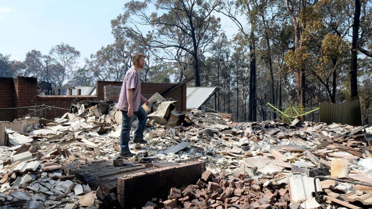 A man inspects the remains of a house in Winmalee