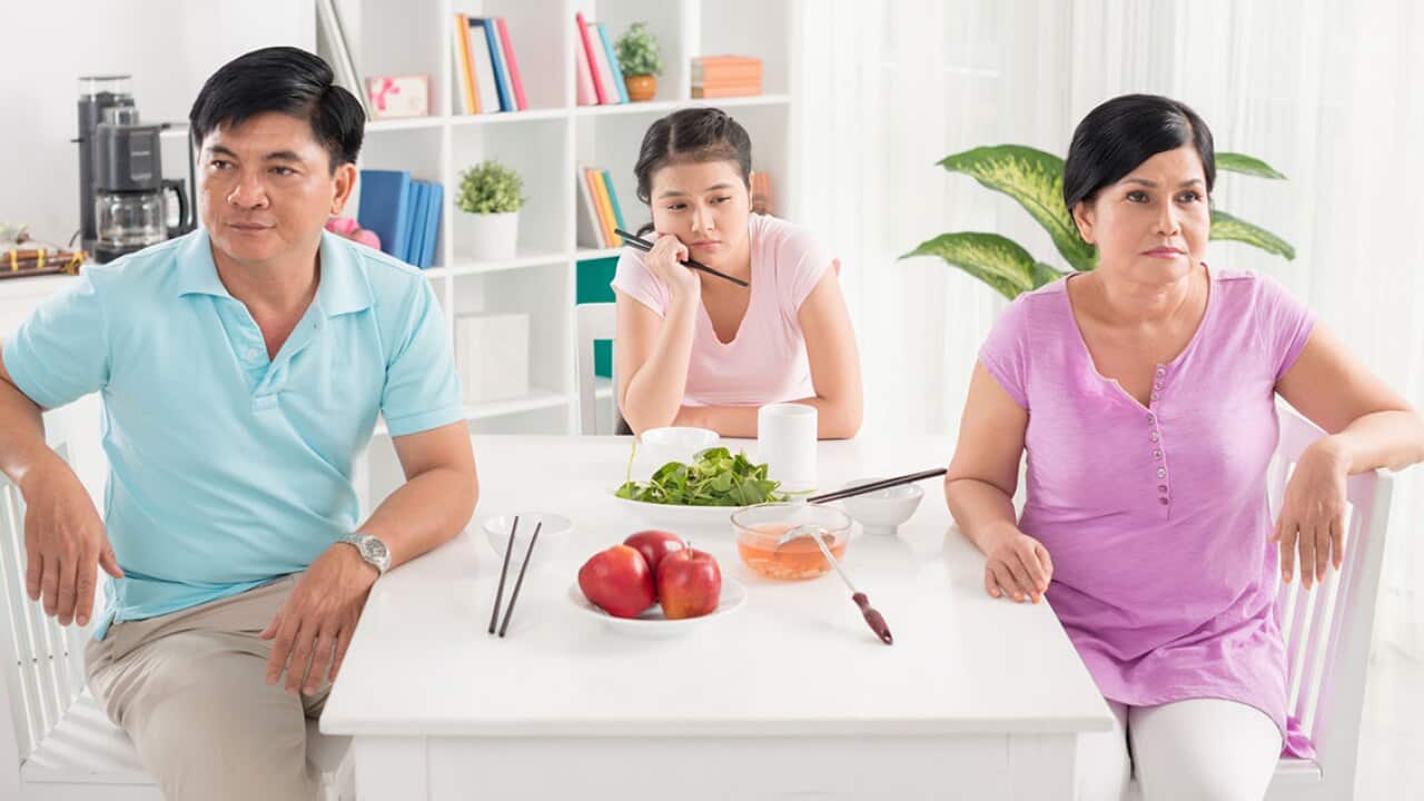 Angry teenage girl with parents at table