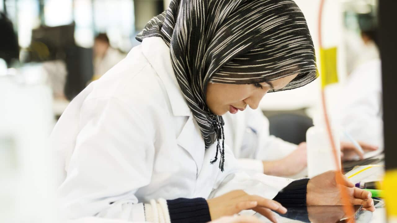 Science student in modern laboratory looking into microscope