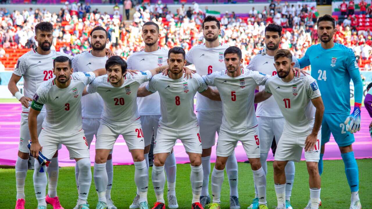 A team of white-jersey-wearing men pose for a photo.
