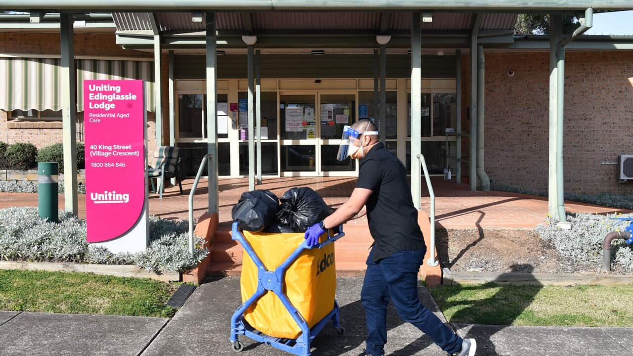 : A cleaner wheels a trolley past an aged care lodge.