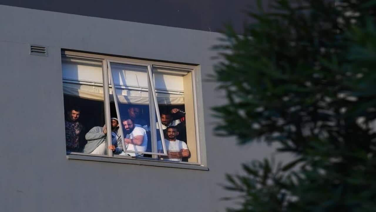 Refugees are seen through a window of the Mantra Hotel