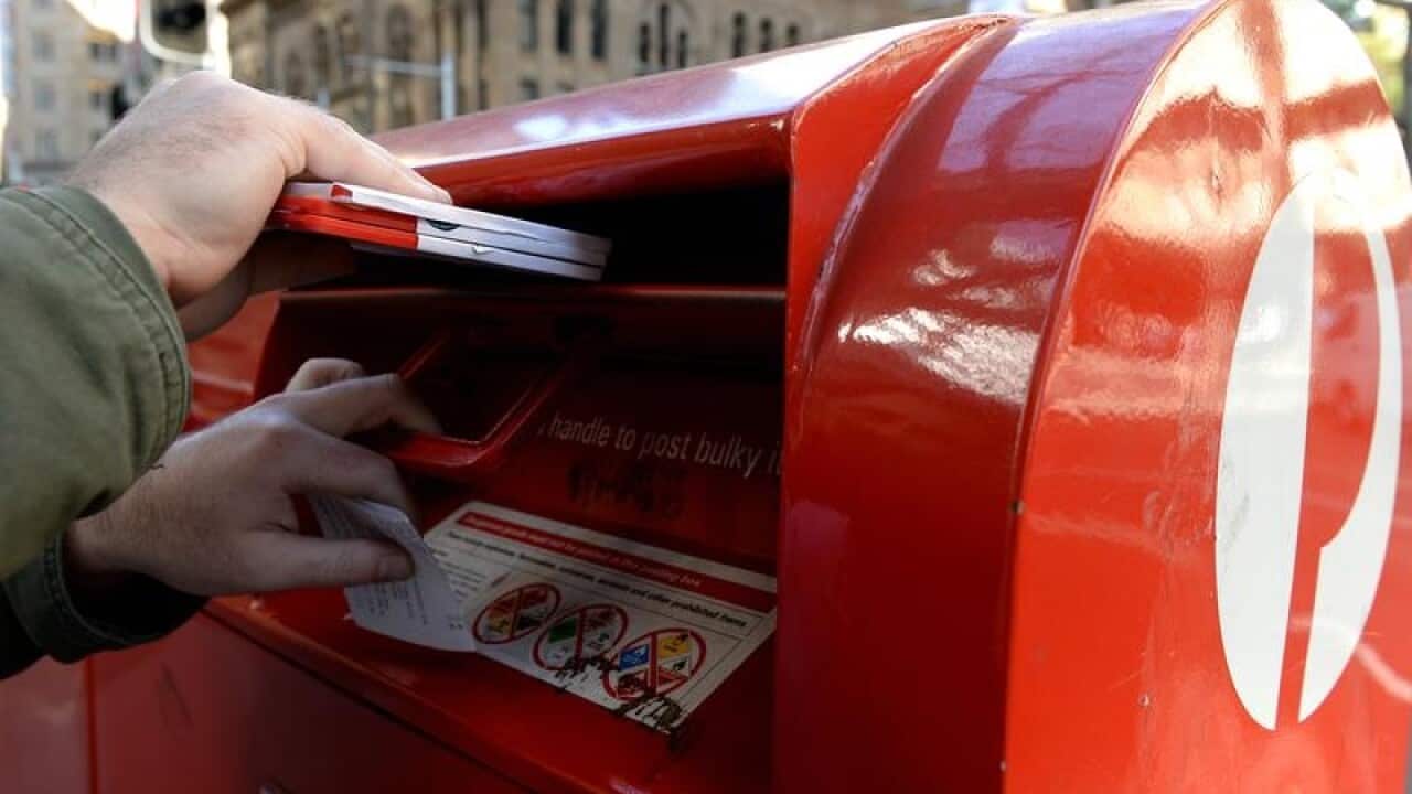 Stock images of a man posting mail at an Australia Post postbox