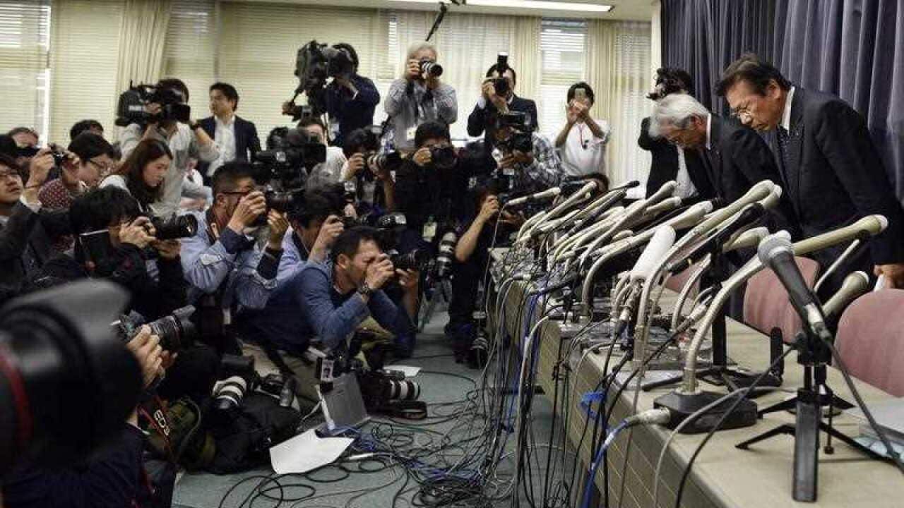 Mitsubishi Motors Corp's President Tetsuro Aikawa (right) bows at the start of a press conference regarding irregular fuel efficiency tests by the carmaker.