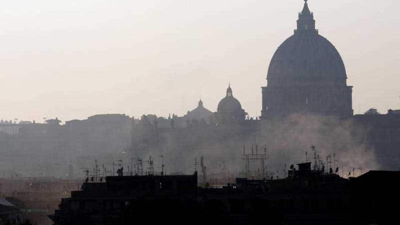 Smoke billows from chimneys in central Rome, in front of St. Peters's Basilica dome.