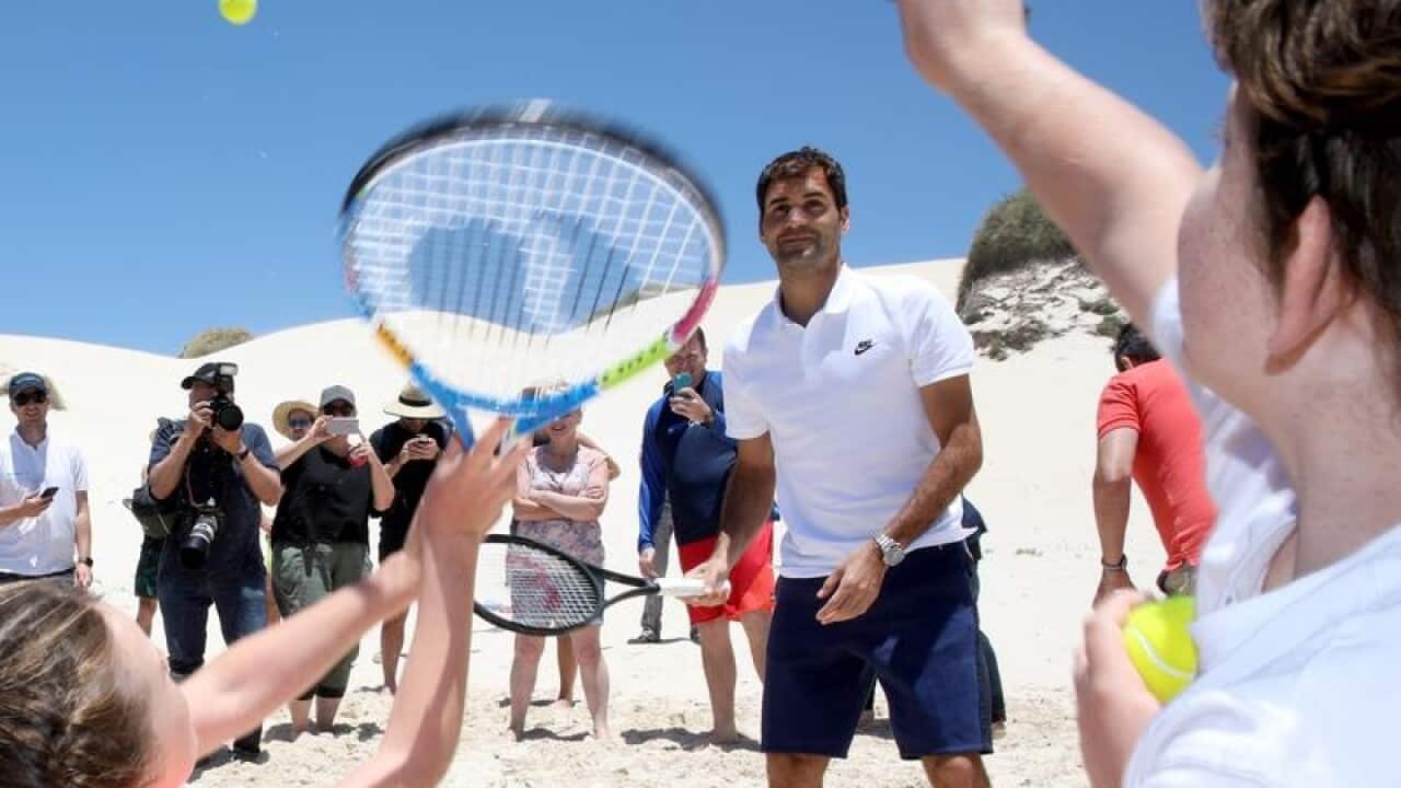 Roger Federer is seen playing beach tennis with children.