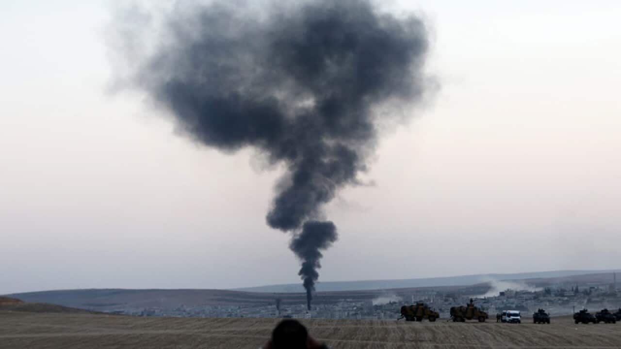 A man looks at smoke rising from an explosion in Kobane, Syria
