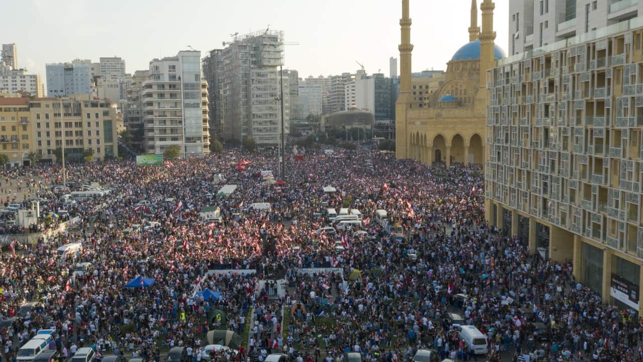 Protesters wave Lebanese flags and shout anti-government slogans during a protest in front of Muhammad al-Amin Mosque in downtown Beirut.