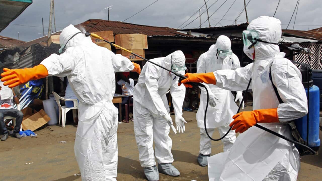 Healthcare workers disinfect one another.