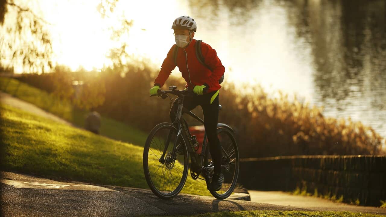 A cyclist is seen wearing a mask along the Yarra River in Melbourne, Friday, July 24, 2020. Victoria is in its second wave of coronavirus deaths and cases, with restrictions in place. (AAP Image/Daniel Pockett) NO ARCHIVING