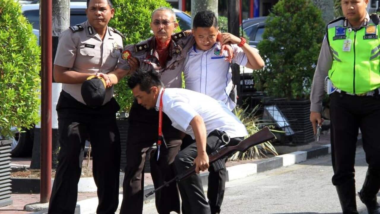 Indonesian police officers evacuate an injured colleague.