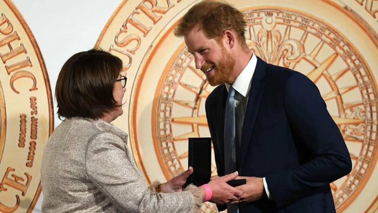 Australian Geographic's Chrissie Goldrick presents Harry with a medal.