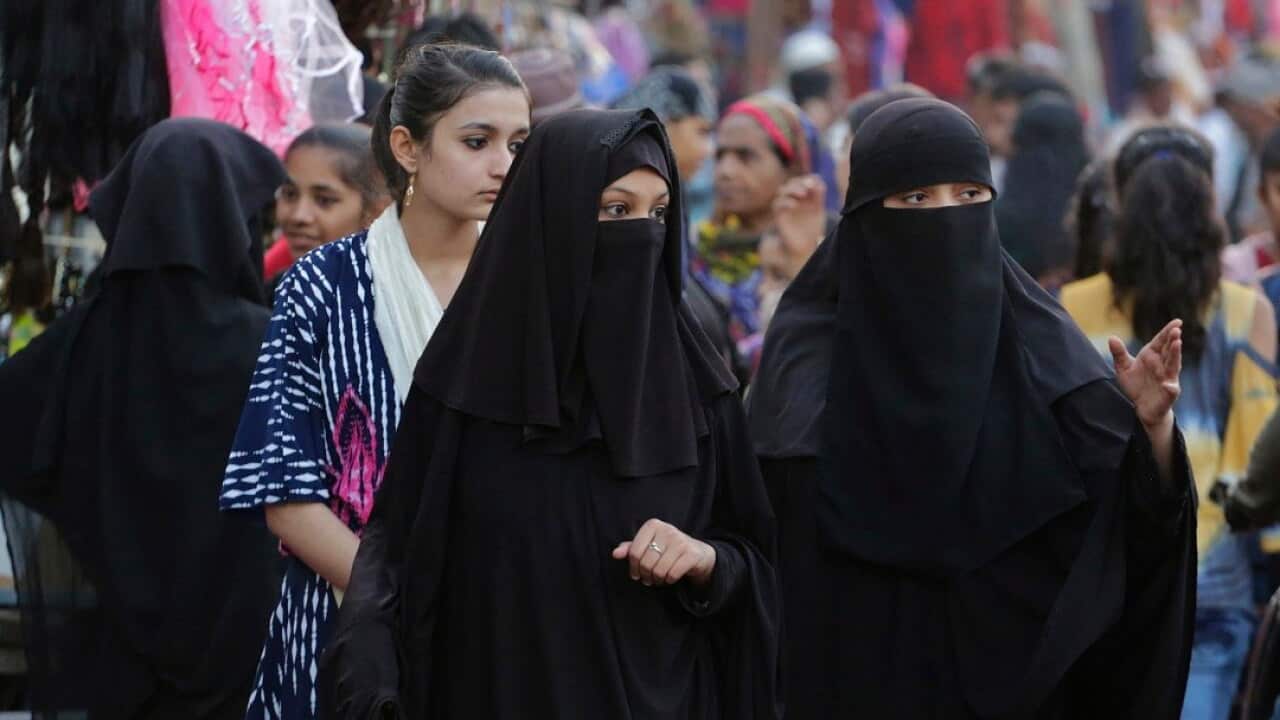Indian Muslim women talk while walking through a market in Ahmadabad, India.