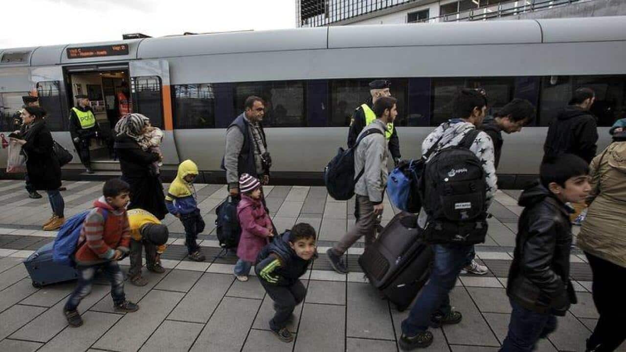 A group of migrants disembark from a train at the Swedish