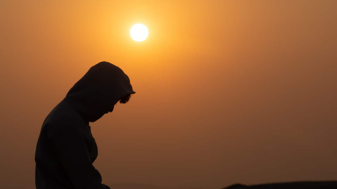 A person wearied hoody sat on the mountain by watching sunset.