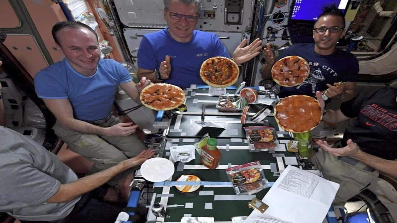 Astronauts on the International Space Station enjoy a meal of pizza.