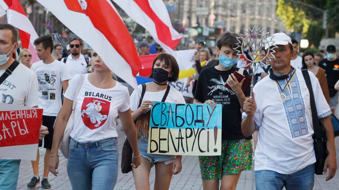 Belarusian citizens in Ukraine hold Belarusian flags during a rally in solidarity with the country's opposition.