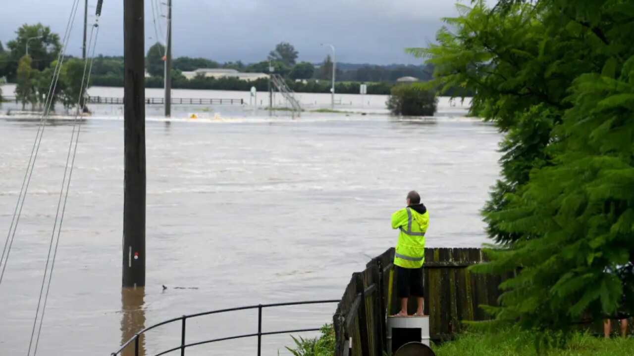 Residents watch over their fence as floodwater rises from the Hawkesbury river at Windsor, north west of Sydney, 3 March, 2022.