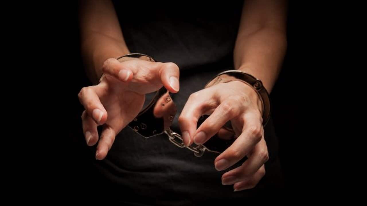 Midsection Of Woman With Handcuffs Against Black Background