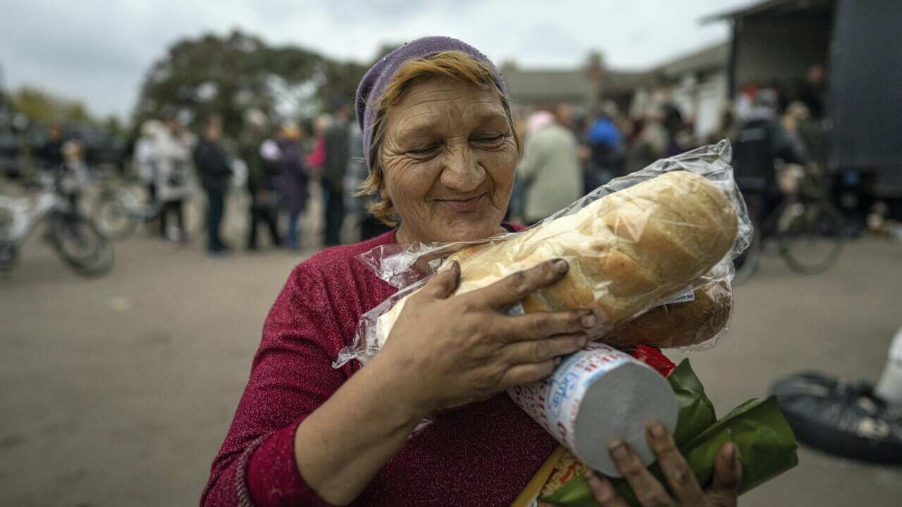 A woman carries humanitarian aid in the recently liberated town of Izium, Ukraine, Sunday, Oct. 2, 2022.