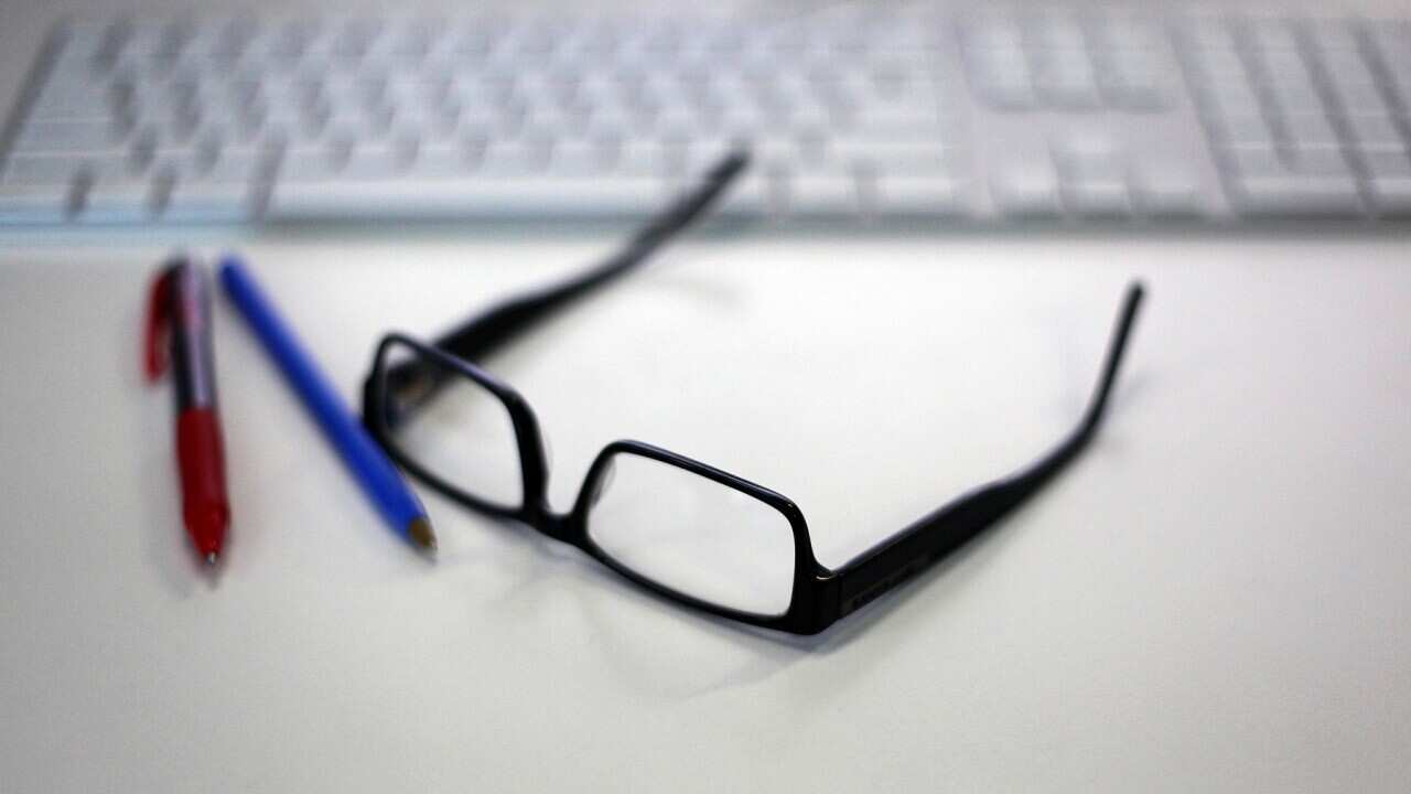 Reading glasses is featured alongside a Macintosh keyboard and office supplies in a stock image in Sydney, Wednesday, Jan. 13, 2016. (AAP Image/Sam Mooy) NO ARCHIVING