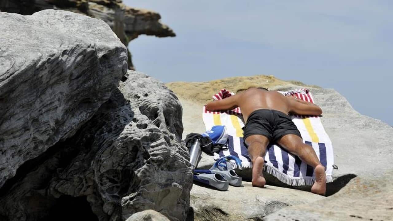 A man sun bakes on the rocks at North Bondi.